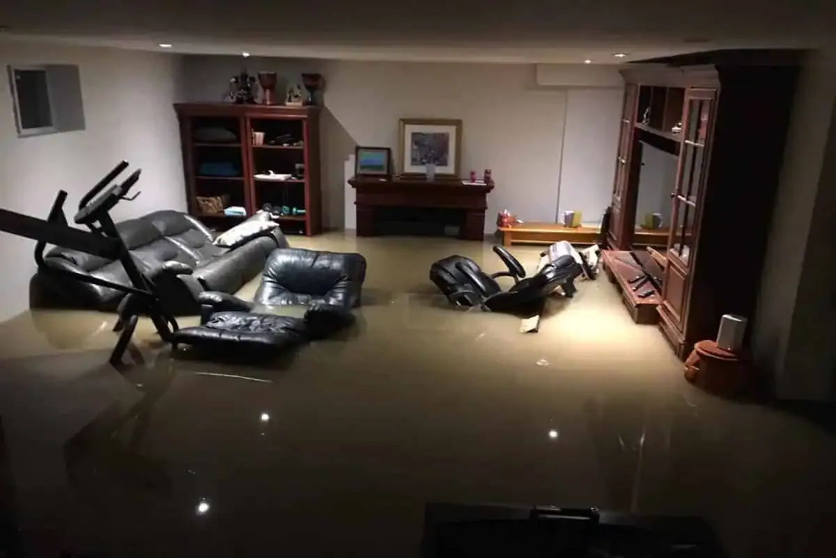 Finished basement with several inches of standing floodwater around couches and shelving