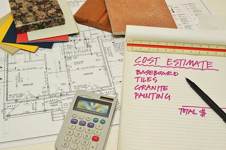 Restoration cost-estimate worksheet on a notepad with house blueprints, a calculator, and material samples